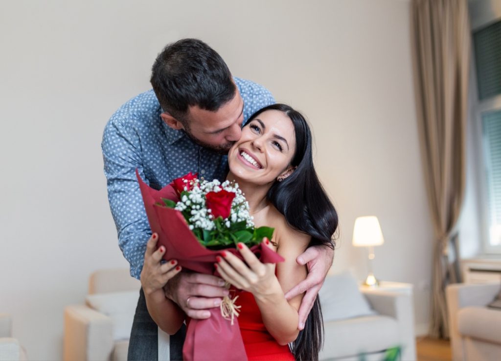 barbat care ii ofera persoanei iubite un buchet de flori